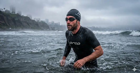 Nadador en la Costa Verde de Lima usando un gorro de neopreno negro y wetsuit durante un día nublado de invierno en aguas abiertas.